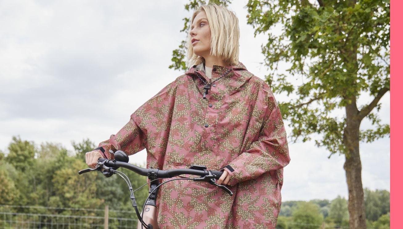 Un femme portant un poncho Rainkiss tenant le guidon du vélo